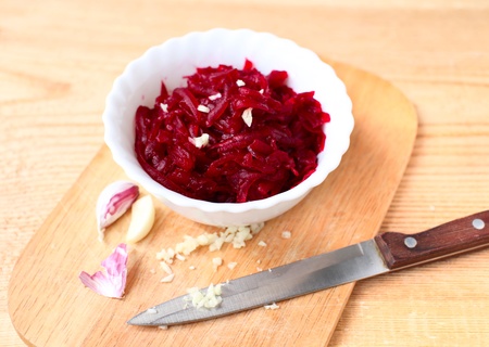 beetroot salad with garlic and oil in a white bowl on wooden tableの写真素材