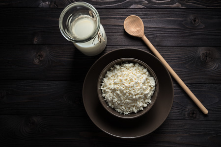 cottage cheese in a brown bowl on a dark wooden backgroundの写真素材