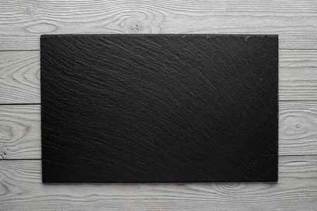 empty piece of slate on a wooden table, horizontal composition