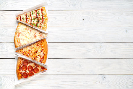 sliced pieces of pizza on a wooden background, top view, place for textの写真素材