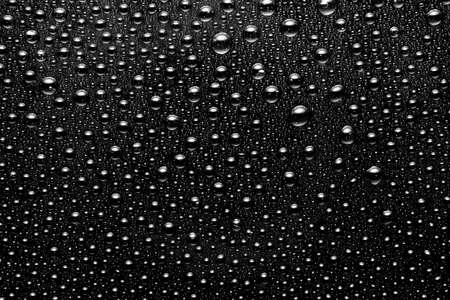 background of drops on a black glossy surface close upの写真素材