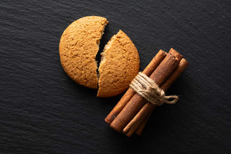 broken oatmeal cookies and cinnamon on a stone background, flat layの写真素材