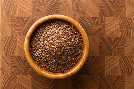 flax seeds in a wooden bowl on a wooden background, top viewの写真素材