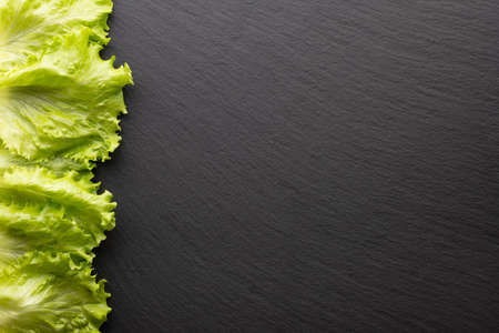 lettuce leaf on black stone background, top view, place for textの写真素材