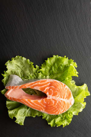 fresh salmon steak on lettuce leaf, stone background, flat lay, place for textの写真素材