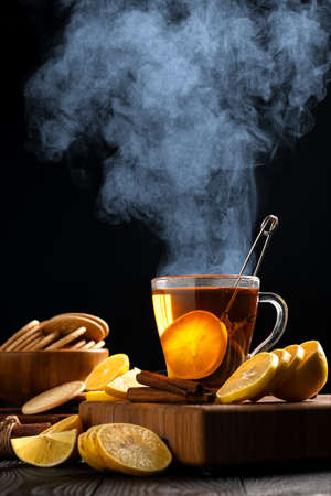 still life with hot tea and lemons, dense steam rises above the mugの写真素材