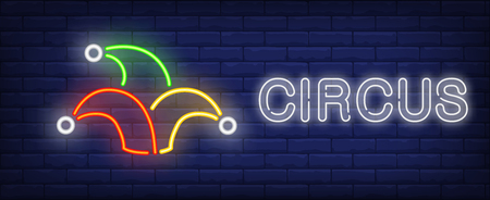Circus neon text with jester hat. Circus performance advertisement design. Night bright neon sign, colorful billboard, light banner. Vector illustration in neon style.のイラスト素材
