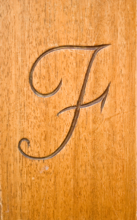 carved engraved calligraphic letter f on a wooden backgroundの写真素材