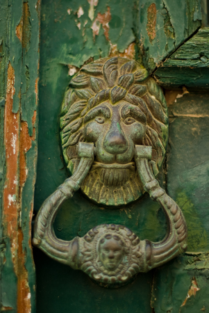 old lion head knocker on a painted aged wooden doorの写真素材