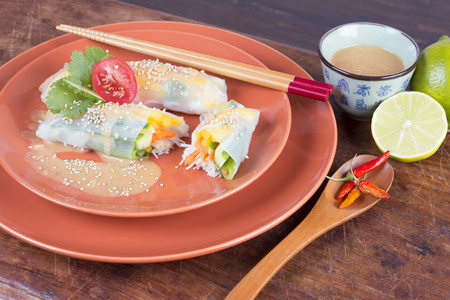 close up of vegan rice paper rolls with tahini dressing and sesame seeds