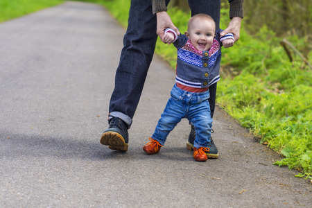 Father guiding his baby with the first stepsの写真素材