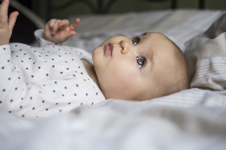close up of a beautiful baby laying on a bedの写真素材