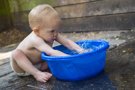 Cute baby playing with a tub of waterの写真素材