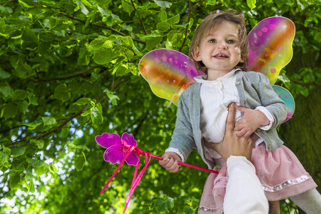 cute little girl with butterfly wings playing in the park