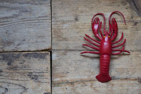 Red plastic lobster on old wooden backgroundの写真素材