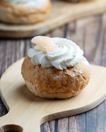 Semla, fastelavnsbolle, fastlagsbulle. On a wooden table with a dark background.