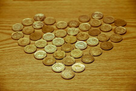 Coin money placed on a wooden table is heart-shaped, love Valentine day.の写真素材