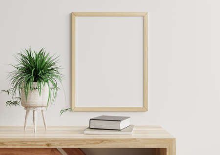 Photo frame mockup on a white wall in the living room, a flower pot and paper placed on a wooden table.3d renderingの写真素材