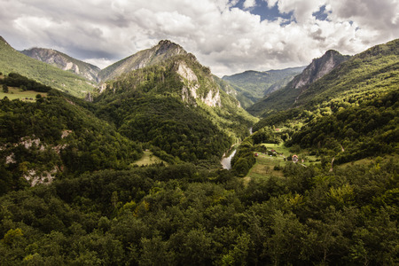 narrow path in green summer mountains with white clouds on blue sky landscapeの写真素材