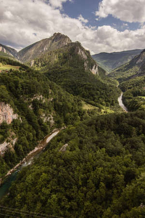 narrow path in green summer mountains with white clouds on blue sky landscapeの写真素材