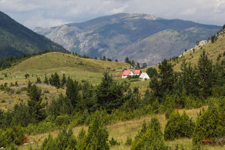 narrow path in green summer mountains with white clouds on blue sky landscapeの写真素材