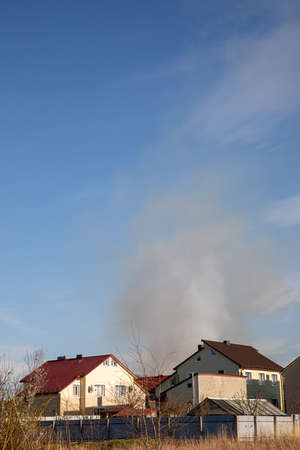 ZYMNA VODA, UKRAINE - APRIL 10, 2020: dark smoke air pollution in ukrainian village with blue sky backgroundのeditorial素材