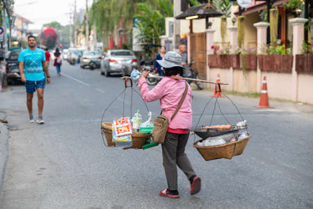 Chianf Mai, Thailand - February 9, 2020: Thai woman carrying traditional basket with eggs and other goods to weekend local market in Chiang Mai in Northern Thailandのeditorial素材