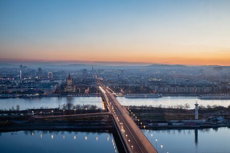 Evening scenic view on Vienna in evening, Donau and Neue Donau with ReichsbrÃ¼cke bridge in dusk, Austrian capital twilight sunset Alps backgroundの写真素材