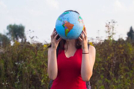 girl with backback holding globe in sunset light backgroundの写真素材