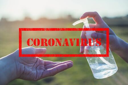 Corona virus sign and transparent white plastic bottle of antibacterial sanitizer fluid in hand pouring into other hand with clear backgroundの写真素材