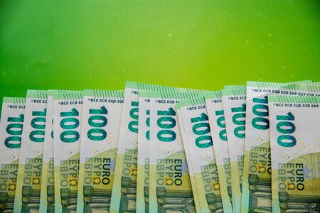 Stack of hundreds of euro banknotes on bright green background with copy spaceの写真素材