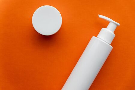 Beauty care products with empty white bottle packages flat lay on bright orange background, hair care and face care itemsの写真素材