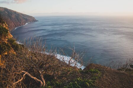 Beautiful scenic sunset view on cliffs coast of Atlantic Ocean with blue breaking waves in Madeira islandの写真素材