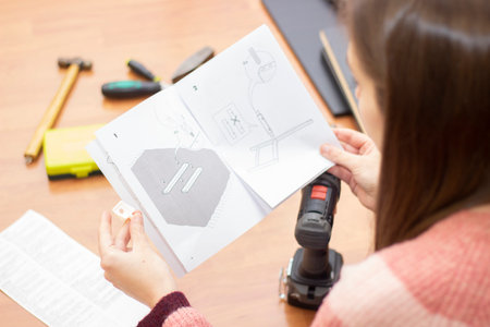 detail of a foreshortened woman reading the assembly instructions of a piece of furnitureの写真素材