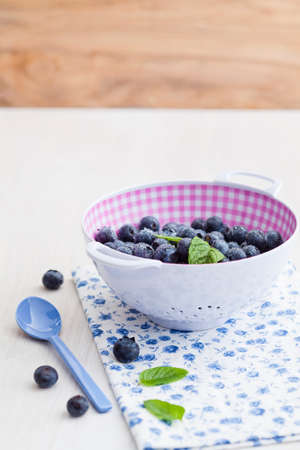 Fresh blueberries in a plastic colander with a spoon
