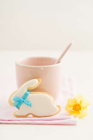 Easter bunny sugar cookie with bow tie and a pink cupの写真素材
