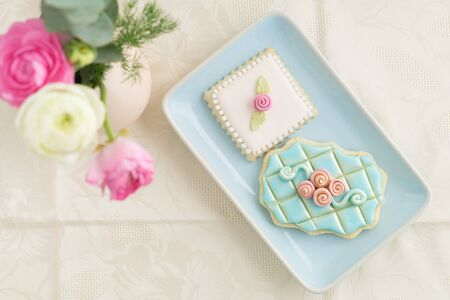 Two decorated and garnished floral sugar cookies on a plate with ranunculus flowersの写真素材