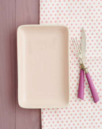 Small empty pink plate on pink tray with pink knife and forkの写真素材