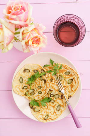 Purple asparagus pancakes on a pink plate with rosesの写真素材