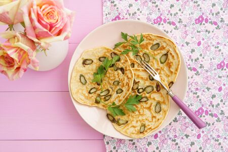 Purple asparagus pancakes on a pink plate with rosesの写真素材