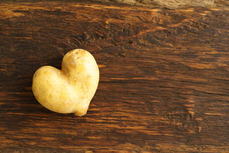 Hear shaped potato and potato on dark woodの写真素材