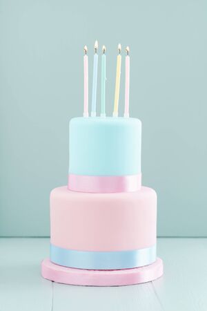 Fondant covered pastels coloured birthday cake with five birthday candlesの写真素材