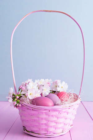 Pink Easter eggs in a pink basket with flowersの写真素材