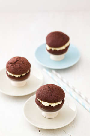 Three chocolate whoopie pies with buttercream filling on cake standの写真素材