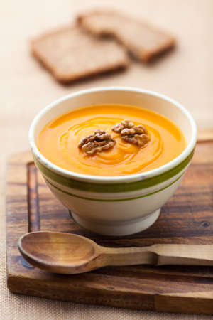 Pumpkin soup from carrots, 2 potatoes and Hokkaido pumpkin decorated with walnuts plus a slice of breadの写真素材