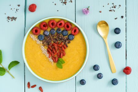 Peach smoothie bowl with blueberries, goji berries, cocoa nibs and raspberries in a bowlの写真素材