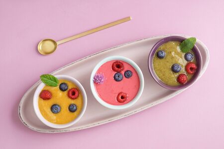 Three smoothie bowls with blueberries, raspberries, kiwi and peachの写真素材