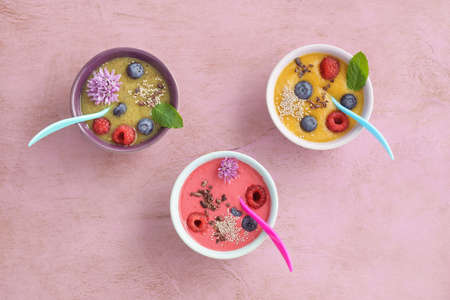 Three smoothie bowls with blueberries, raspberries, kiwi and peachの写真素材