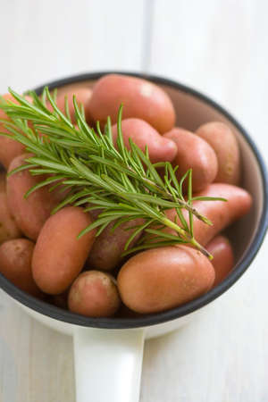 Potatoes with rosemary twig in a vintage enamel skilletの写真素材
