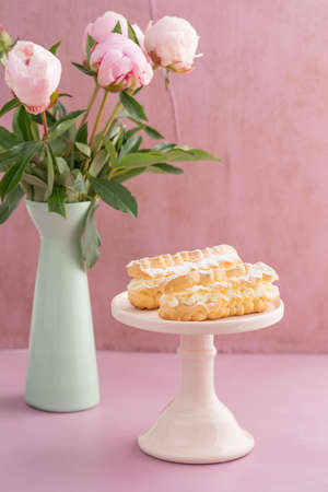 Eclairs with buttercream filling on a pink cake standの写真素材